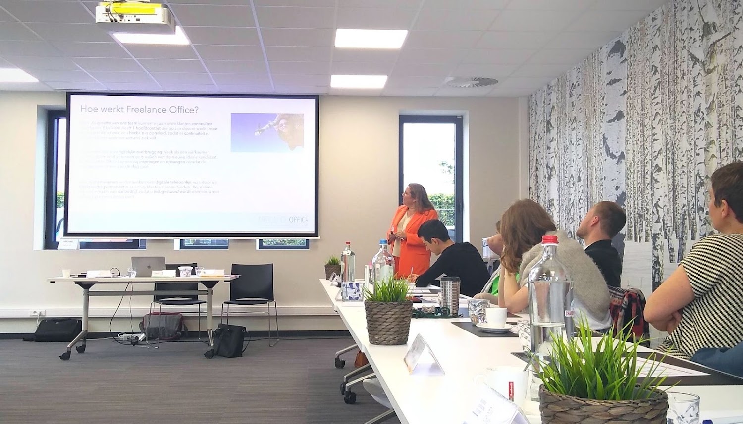 Mensen zitten in een kantoorruimte en kijken naar een Freelance Office presentatie. Ups and downs ondernemers: upside is netwerken zoals hier bij BNI Leuven. 
