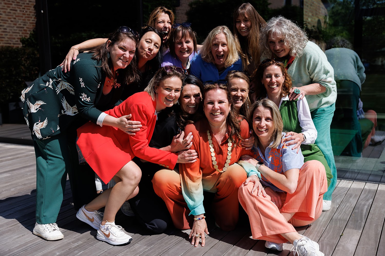 Een team van 12 vrouwen zit vrolijk lachend en gehurkt rondom zaakvoerster Saartje in het midden